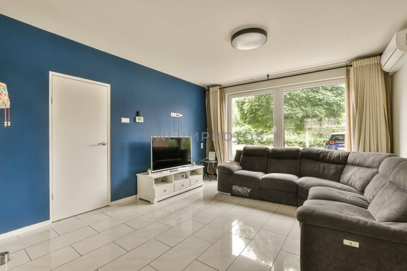 a living room with a blue wall and a tv by casamedia