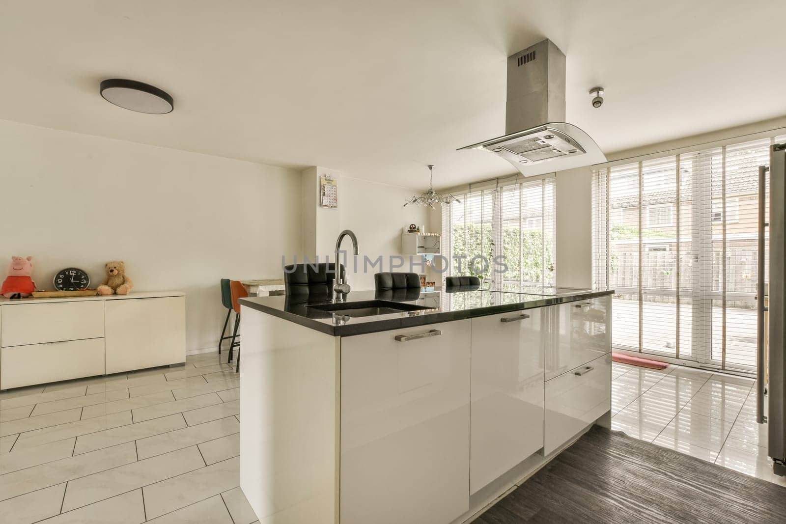 a kitchen area with white cabinets and black counter tops in the center of the image is an open door leading outside patio