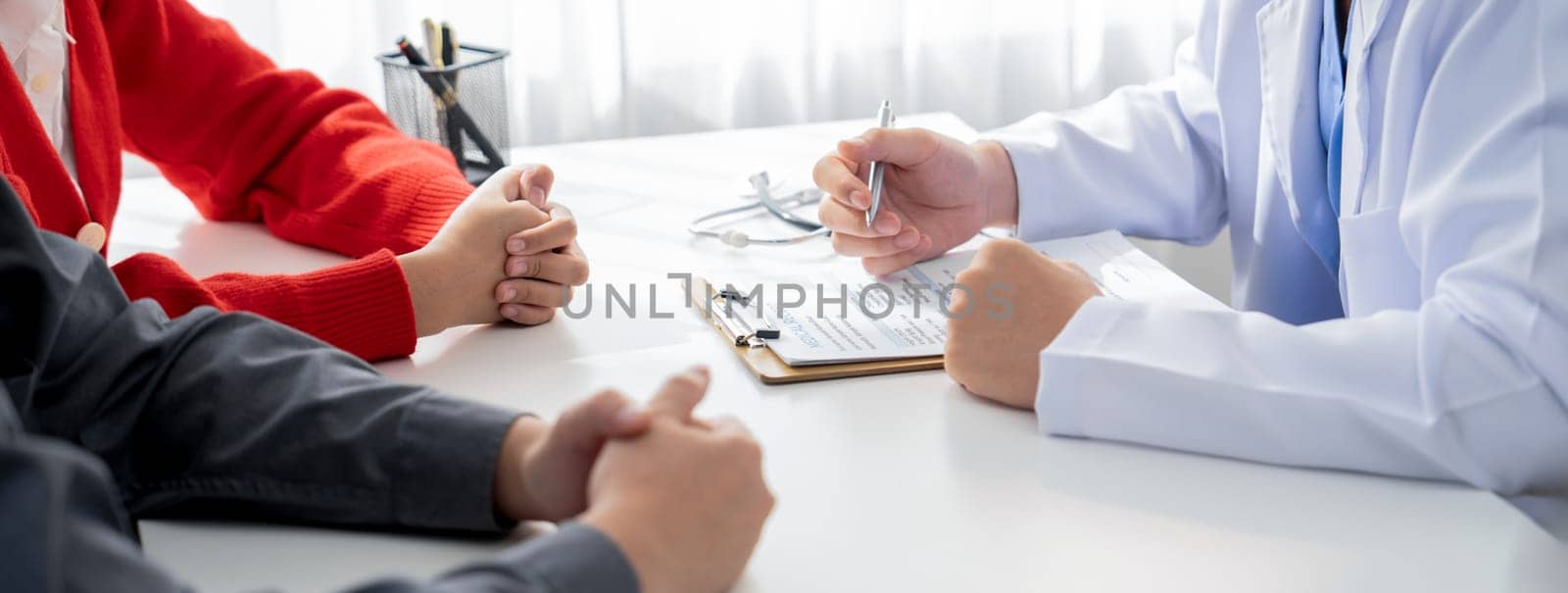 Couple attend fertility consultation with gynecologist at hospital as part family planning care for pregnancy. Loving husband and wife support each other through the doctor appointment. Panorama Rigid