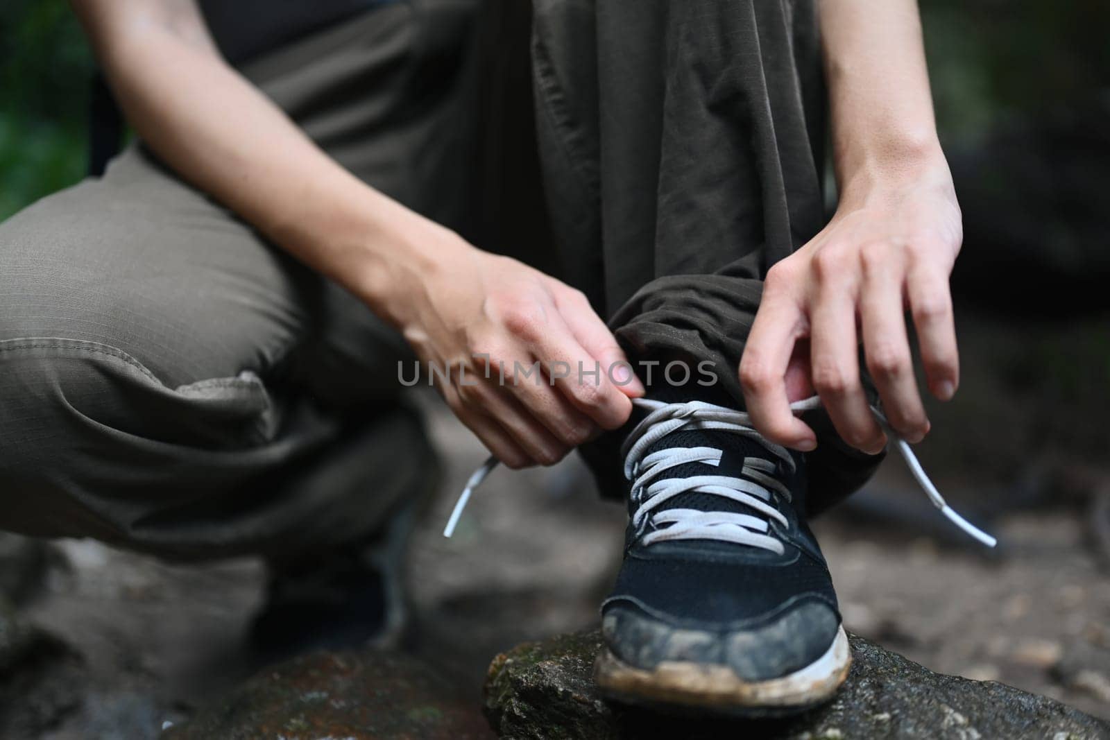 Female hiker tying shoelaces, getting ready walking in forest. Active life, adventure and healthy lifestyle by prathanchorruangsak