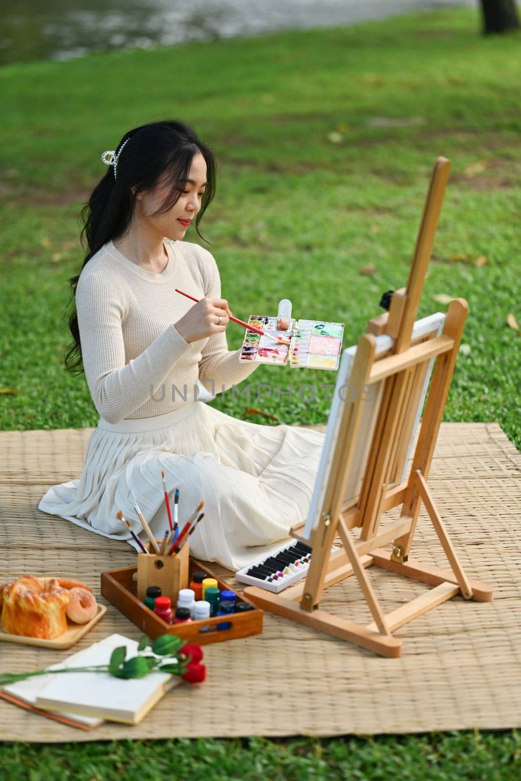 Talented young woman painting on canvas in the park. Art and leisure activity concept.