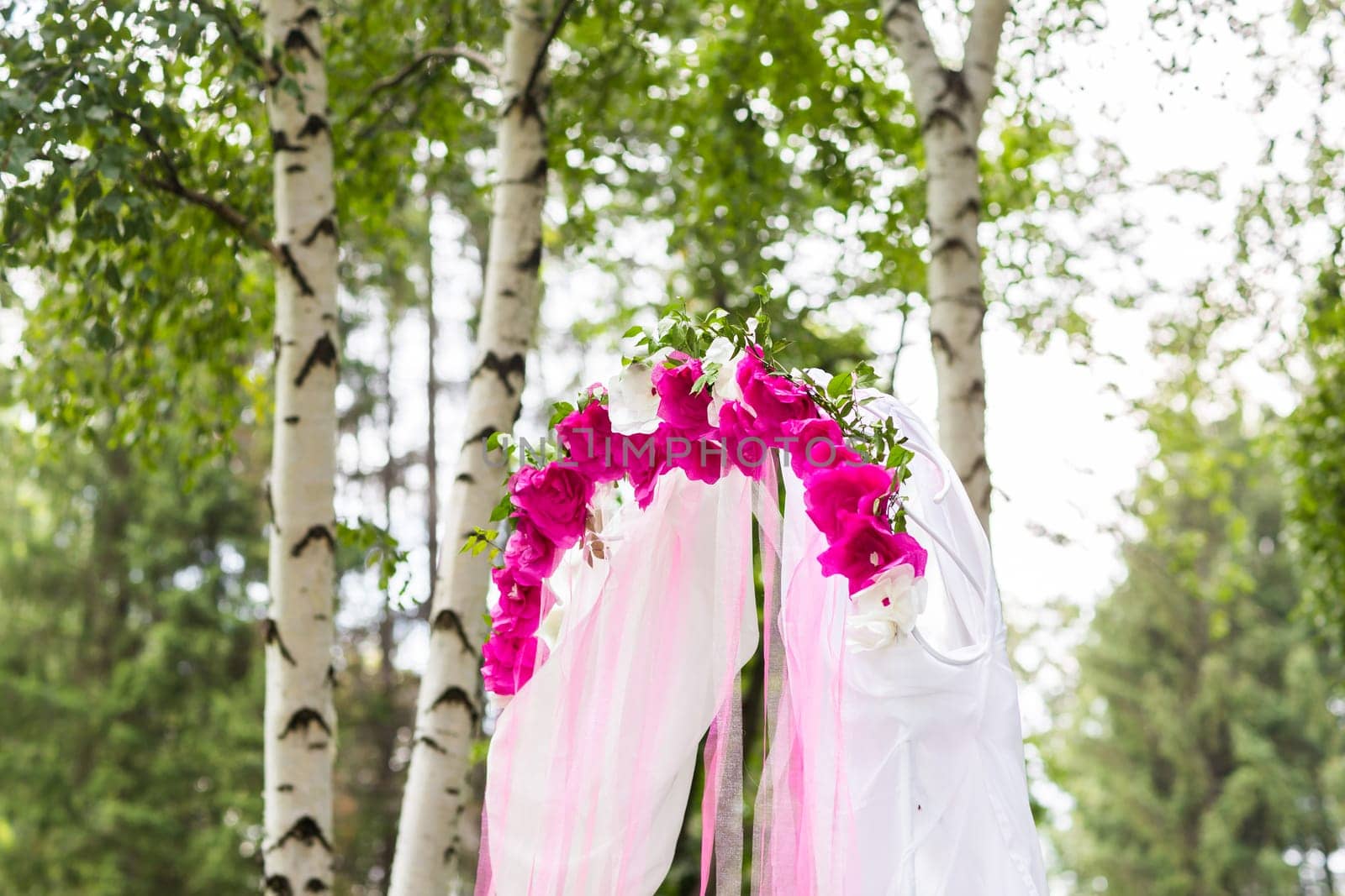 Beautiful wedding arch decorated with pink and red flowers indoors.