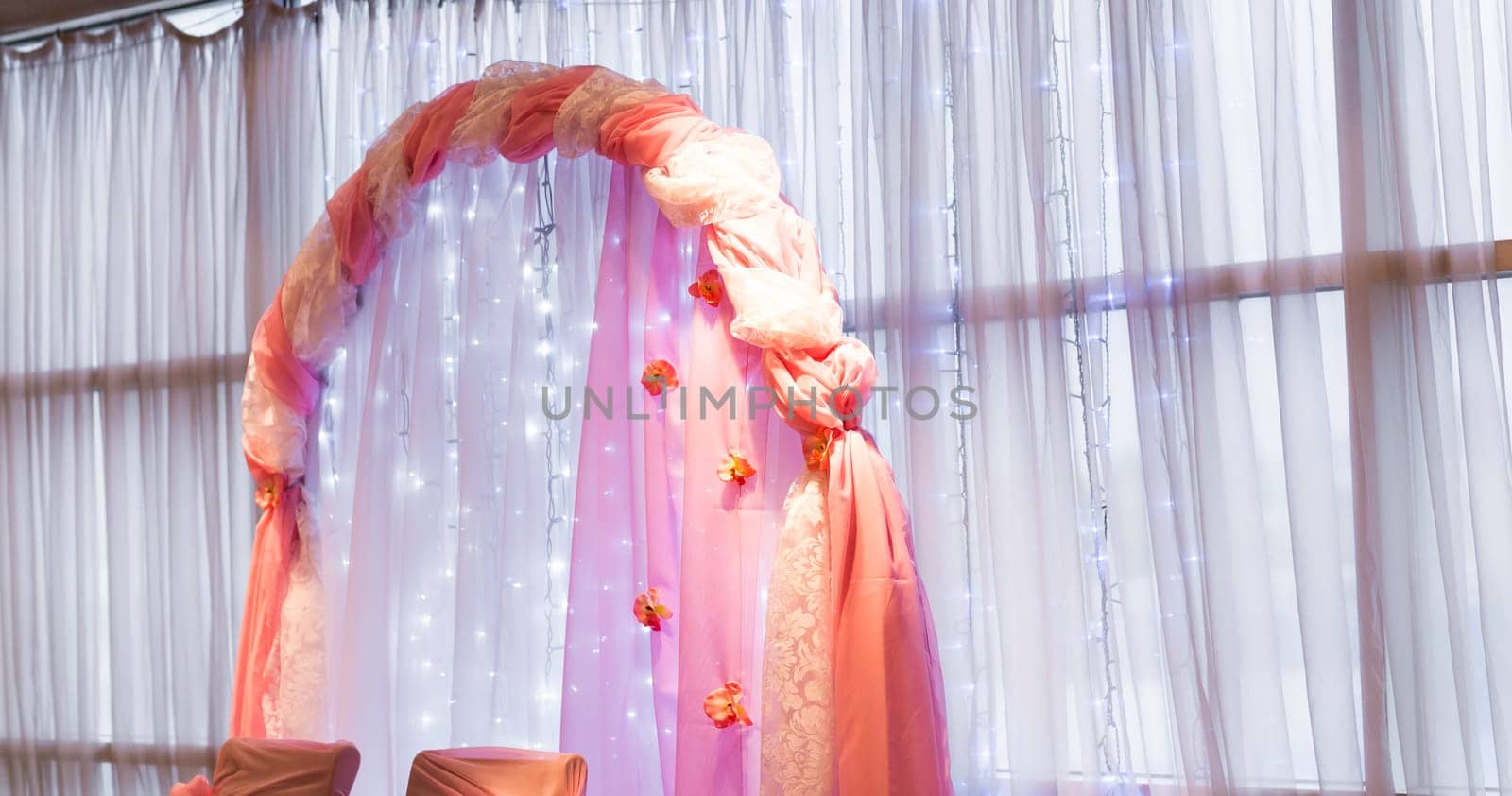 Beautiful wedding arch decorated with pink and red flowers indoors.