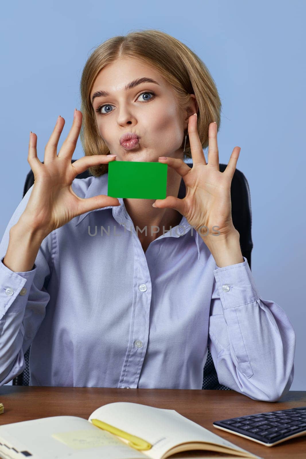 beautiful blonde businesswoman holding plastic credit card on blue background