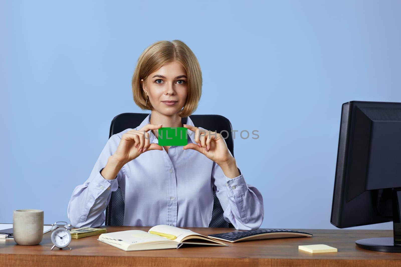 beautiful blonde businesswoman holding plastic credit card on blue background