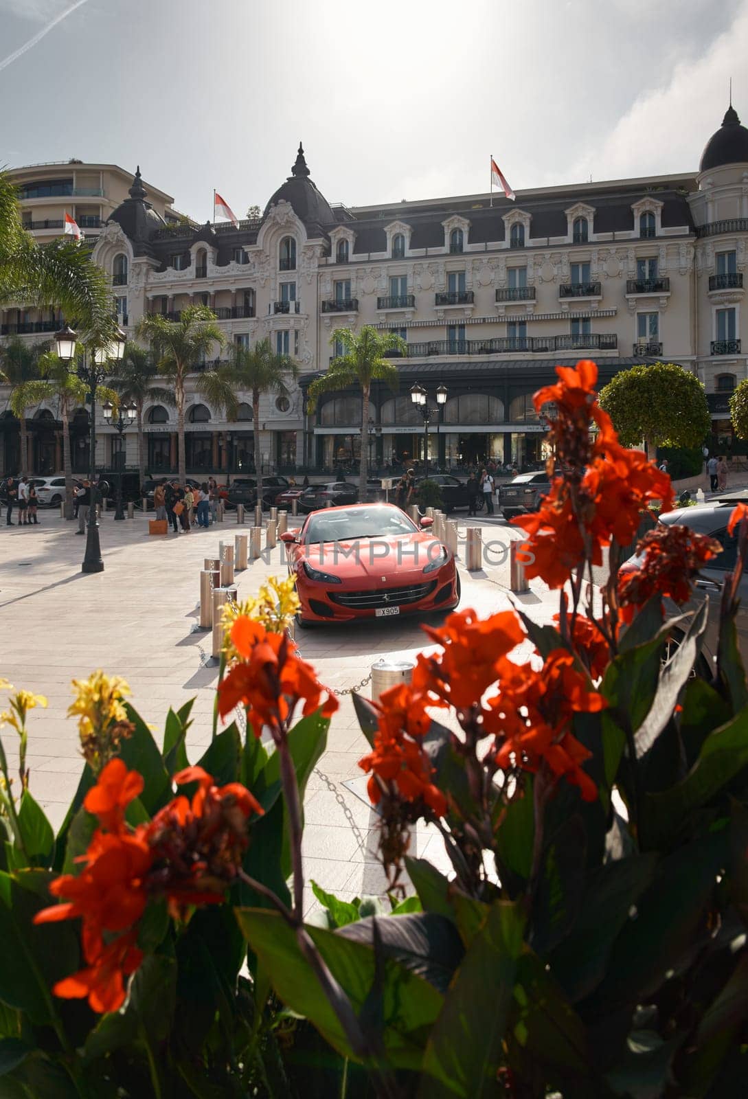 Monaco, Monte-Carlo, 22 October 2022: Square Casino Monte-Carlo at sunset, luxury cars, famous Hotel de Paris, wealth life, tourists take pictures of the landmark, pine trees, flowers. High quality photo