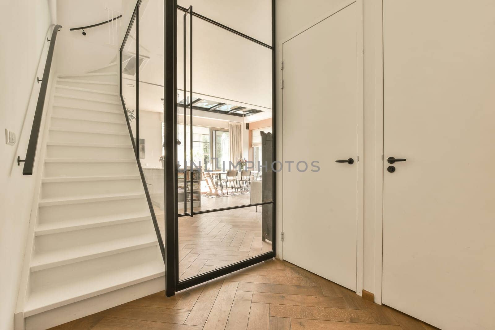 the inside of a house with wood flooring and white walls, stairs leading up to an open door that leads to another room