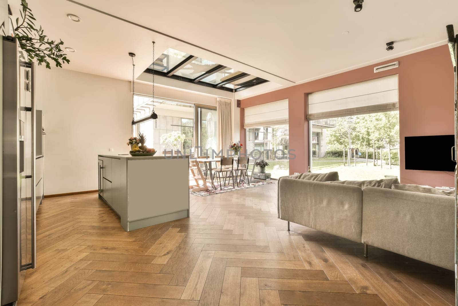 a living room with wood flooring and an open door leading to the kitchen area in the room is bright pink