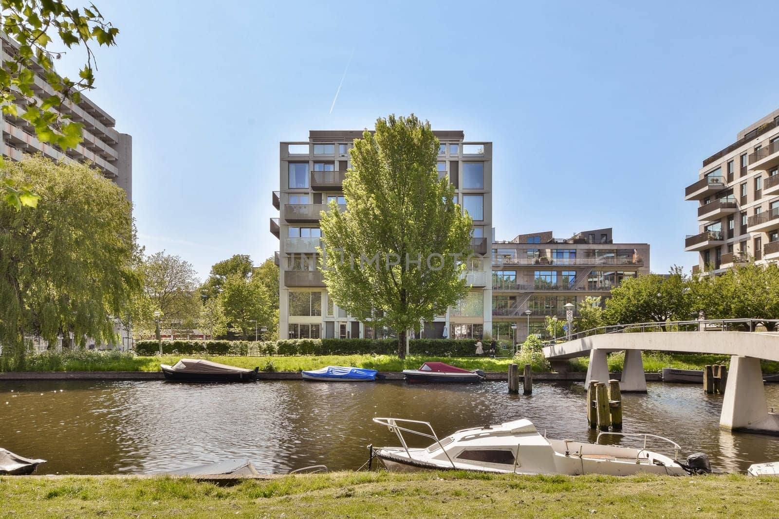 some boats in the water and buildings on the other side of the river, with trees lining the banks behind