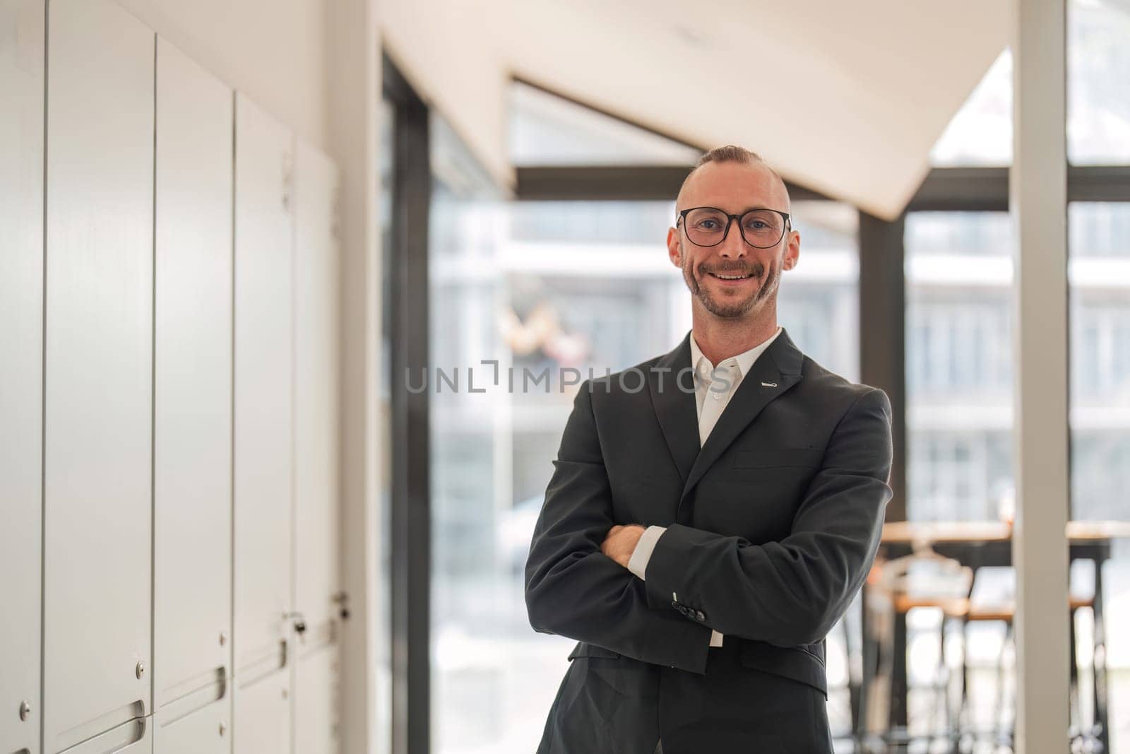 Portrait of an attractive young businessman A successful business executive stands with his arms crossed in his office with a happy smile on his face..