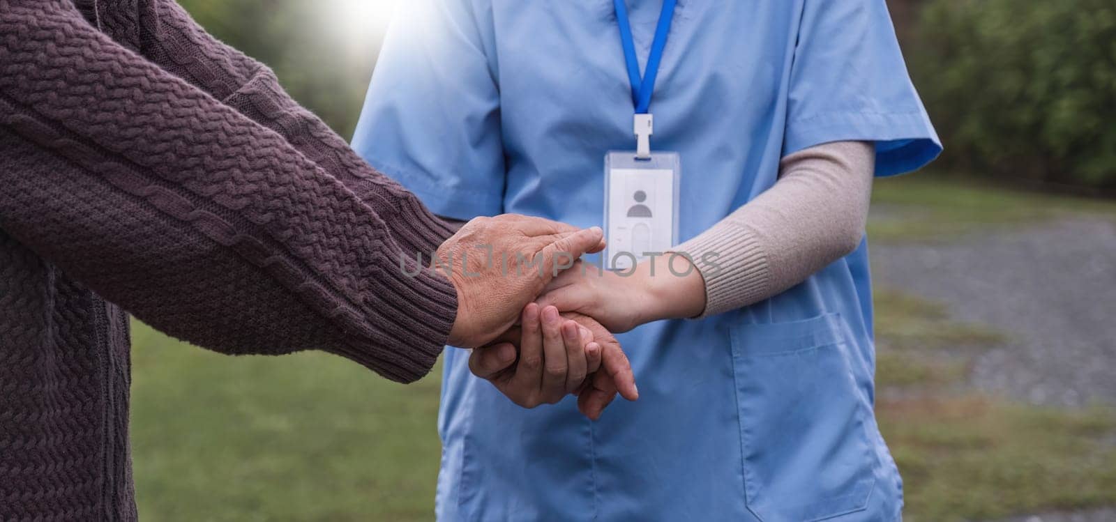 close up, an elderly male patient holds hands with a nurse who comes to take care of and help encourage each other..