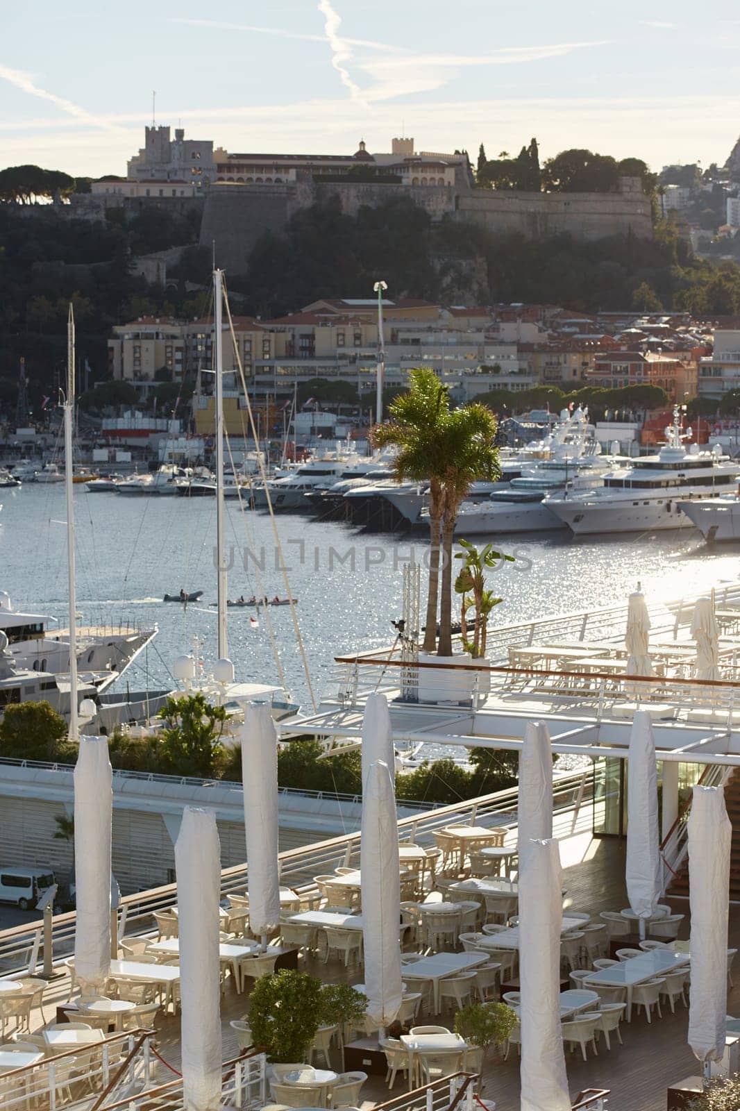 Monaco, Monte Carlo, 18 October 2022: Sunset panorama of port Hercule, moored mega yacht, sun reflection. High quality photo