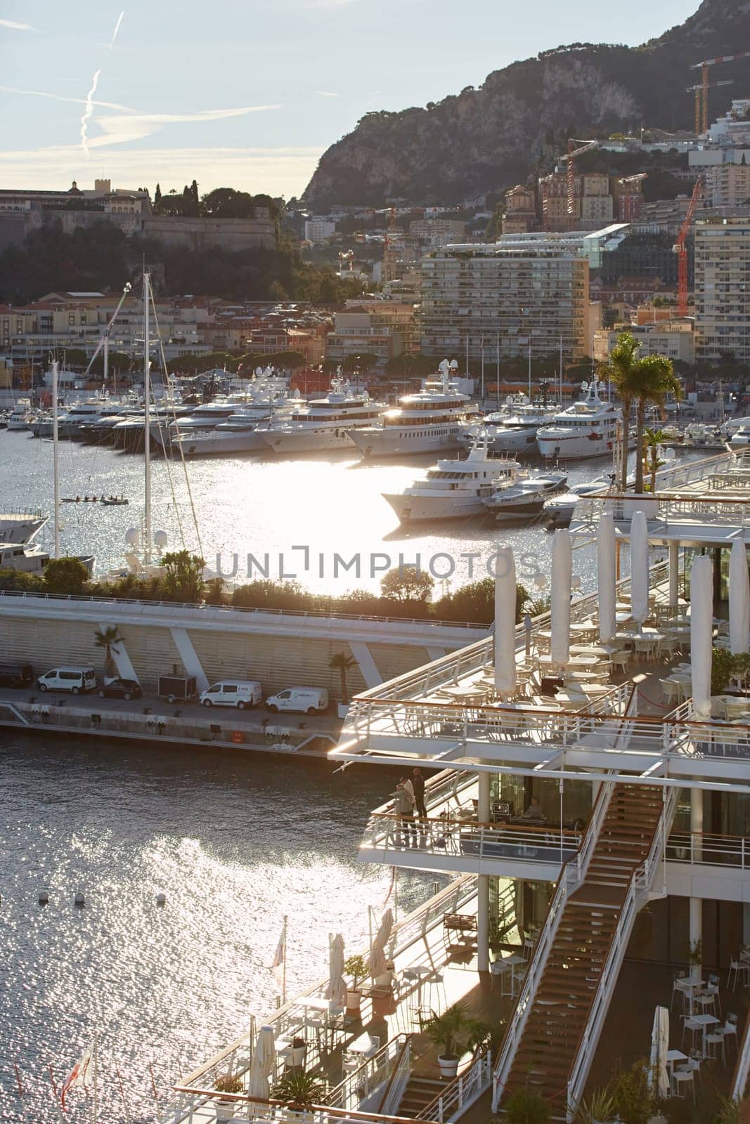 Monaco, Monte Carlo, 18 October 2022: Sunset panorama of port Hercule, moored mega yacht, sun reflection. High quality photo