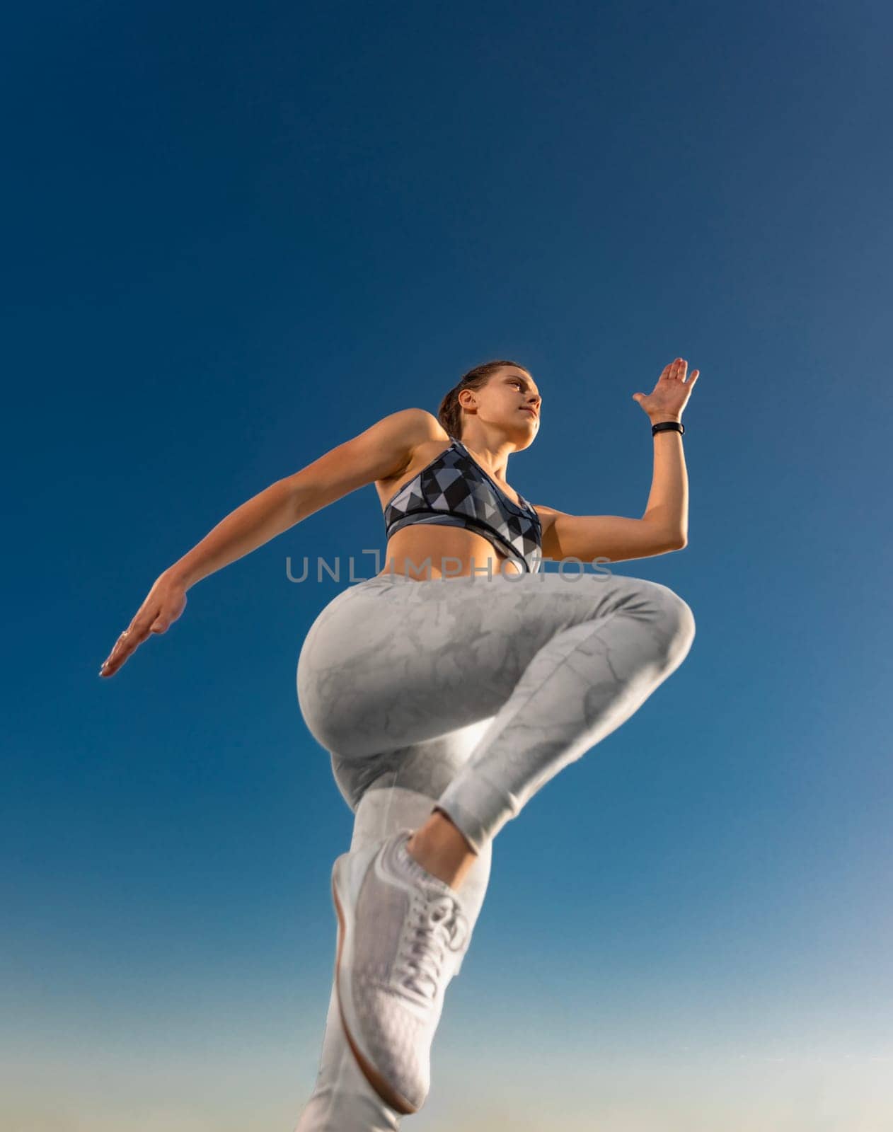 Runner concept. Jogging run. Strong athletic woman jumping on sky background wearing in the sportswear. Fitness and sport motivation. by MikeOrlov