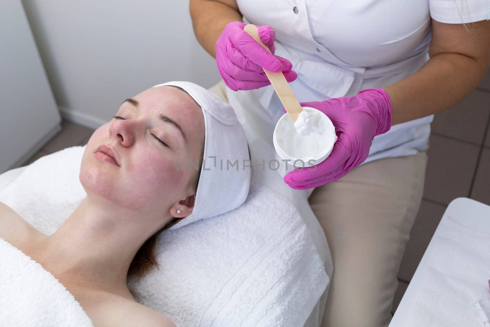 Cropped Cosmetologist, Beautician Applying Moisturizing Mask, Cream On Woman's Red Skin After Chemical Peeling In Beauty Salon. Cosmetology And Face Skin Care. Facial Treatment. Horizontal Plane.