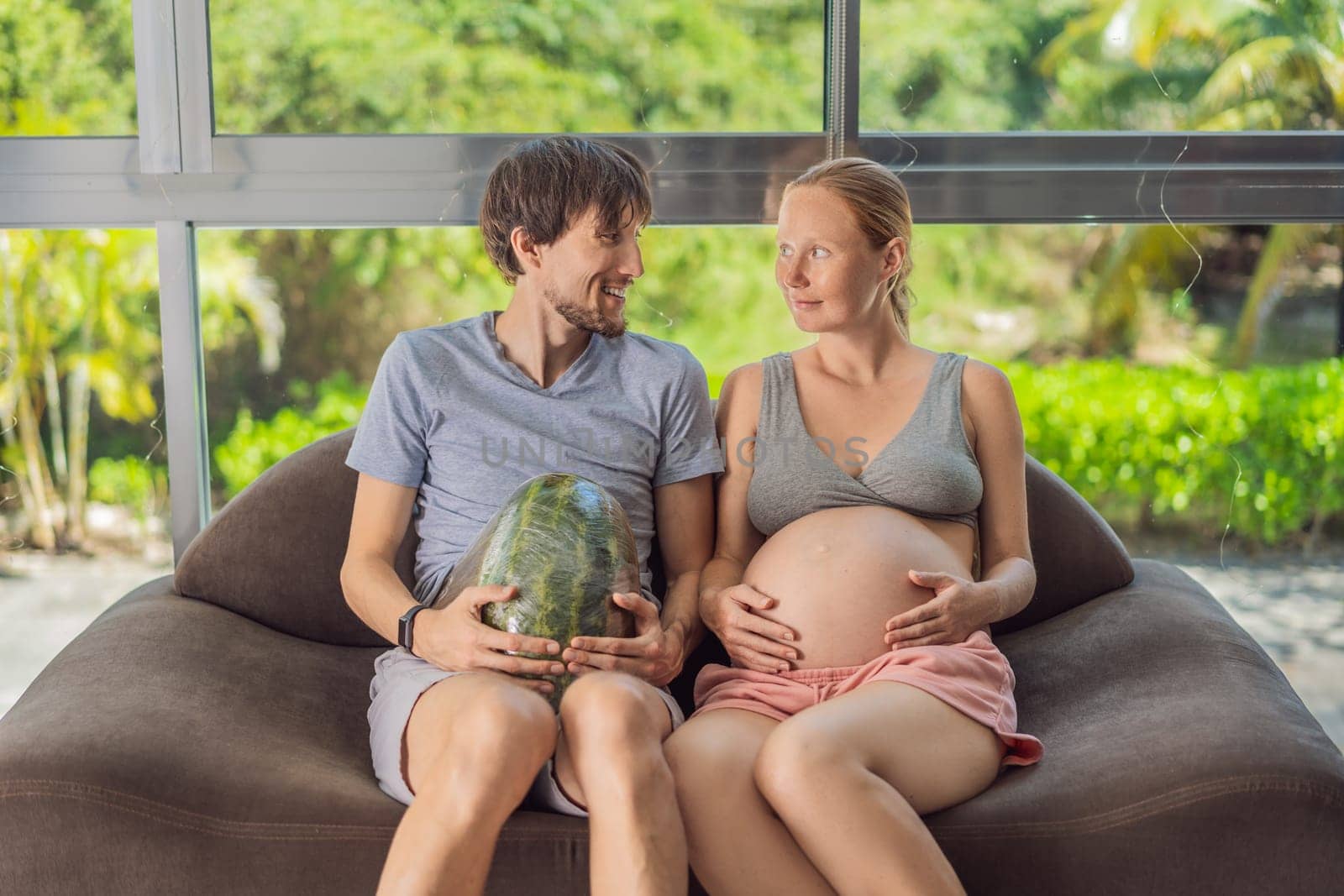 A humorous image: a pregnant woman and her husband playfully use a watermelon in place of a belly, comically highlighting the challenges of navigating with a pregnant bump.