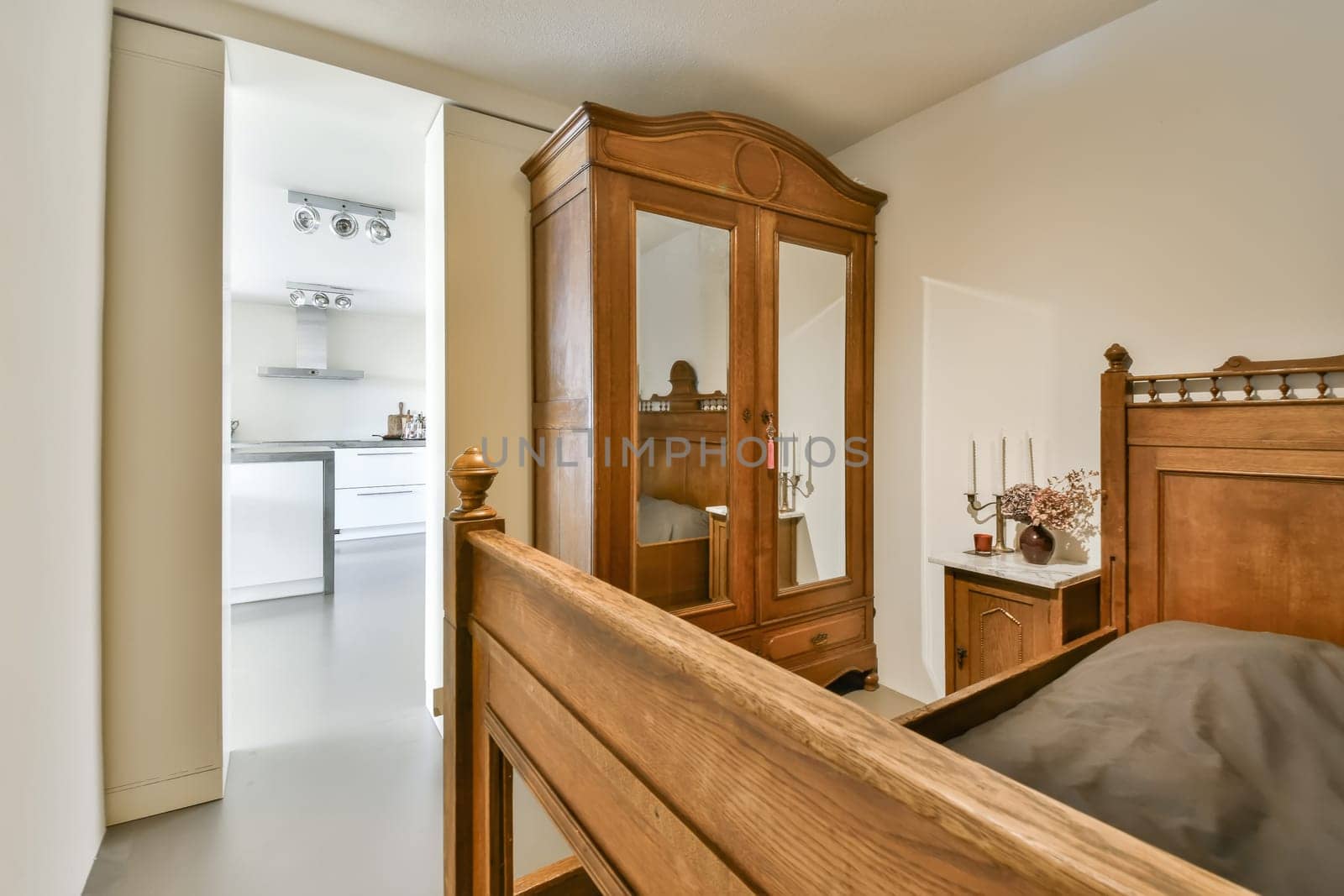 a bedroom with a bed, dresser and mirror on the wall in front of the door that leads to another room