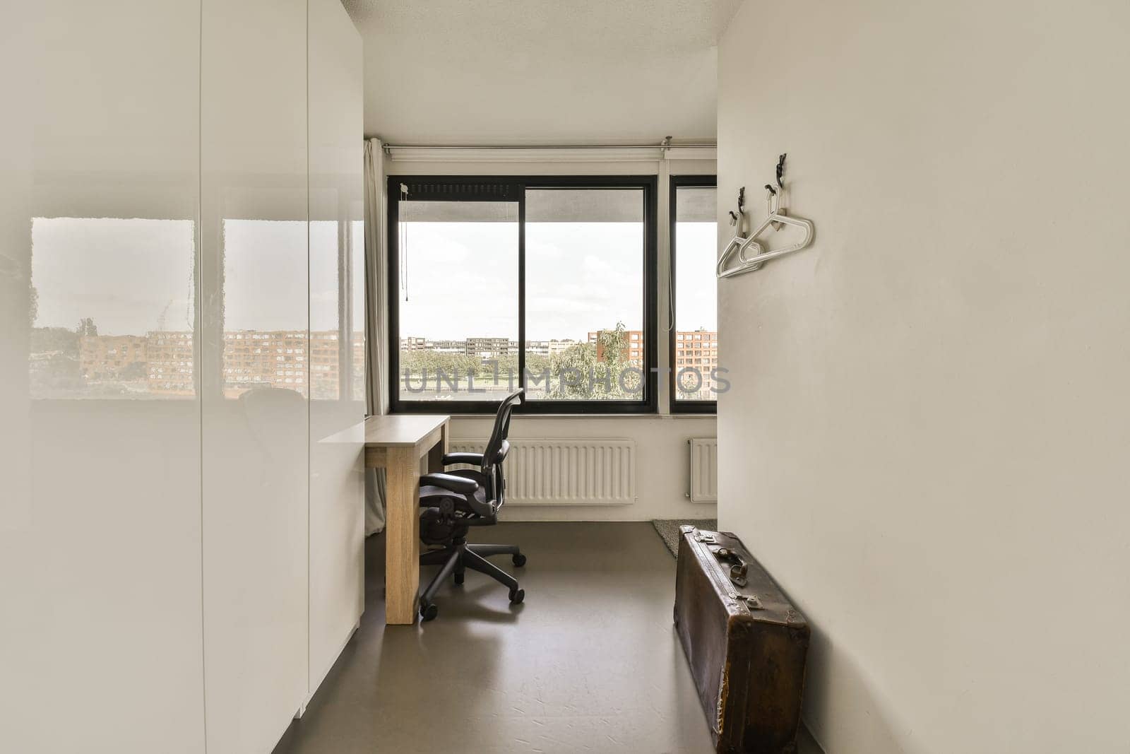 a room with a desk, chair and large window looking out onto the cityscapearrons com