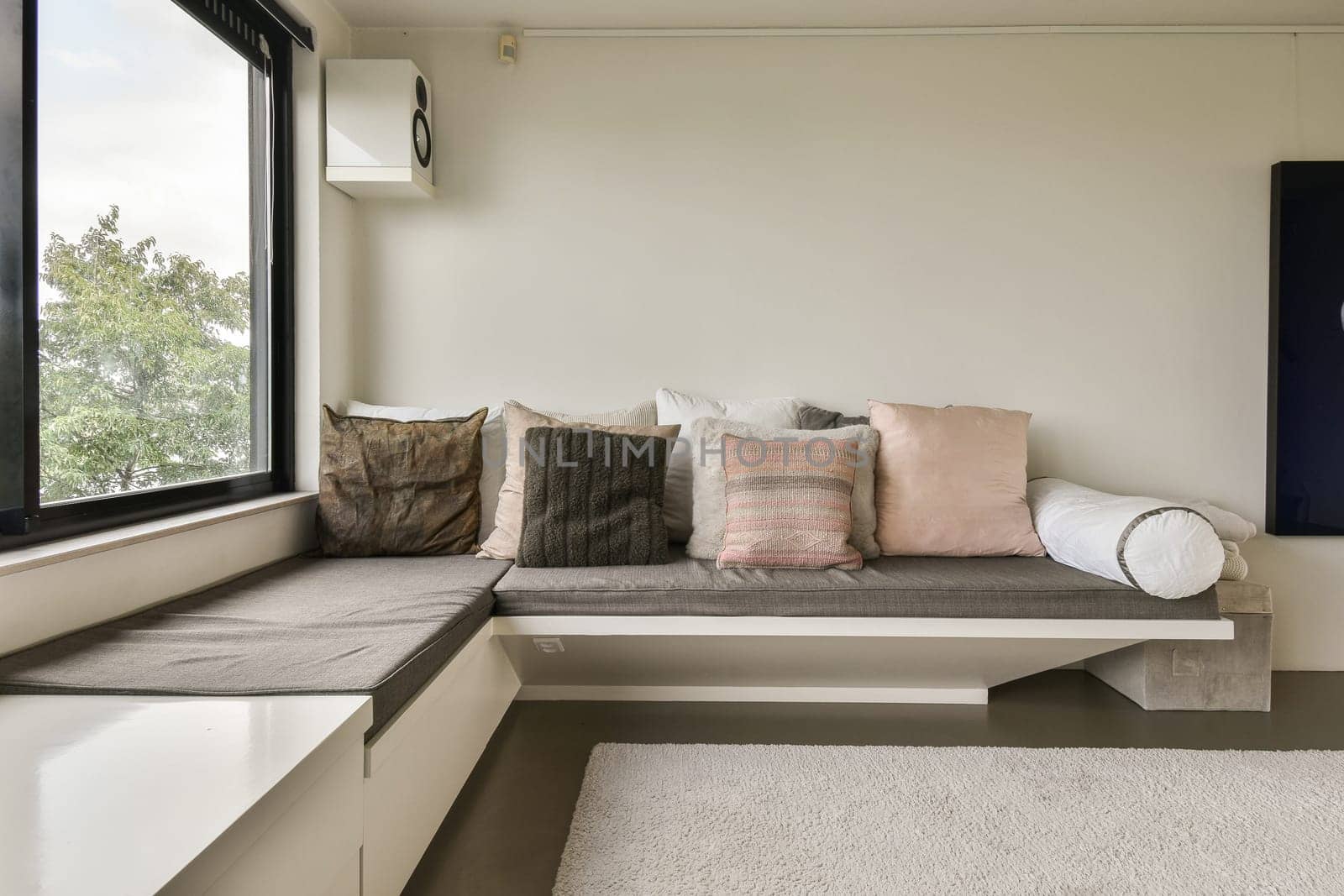 a seating area with pillows and a window by casamedia