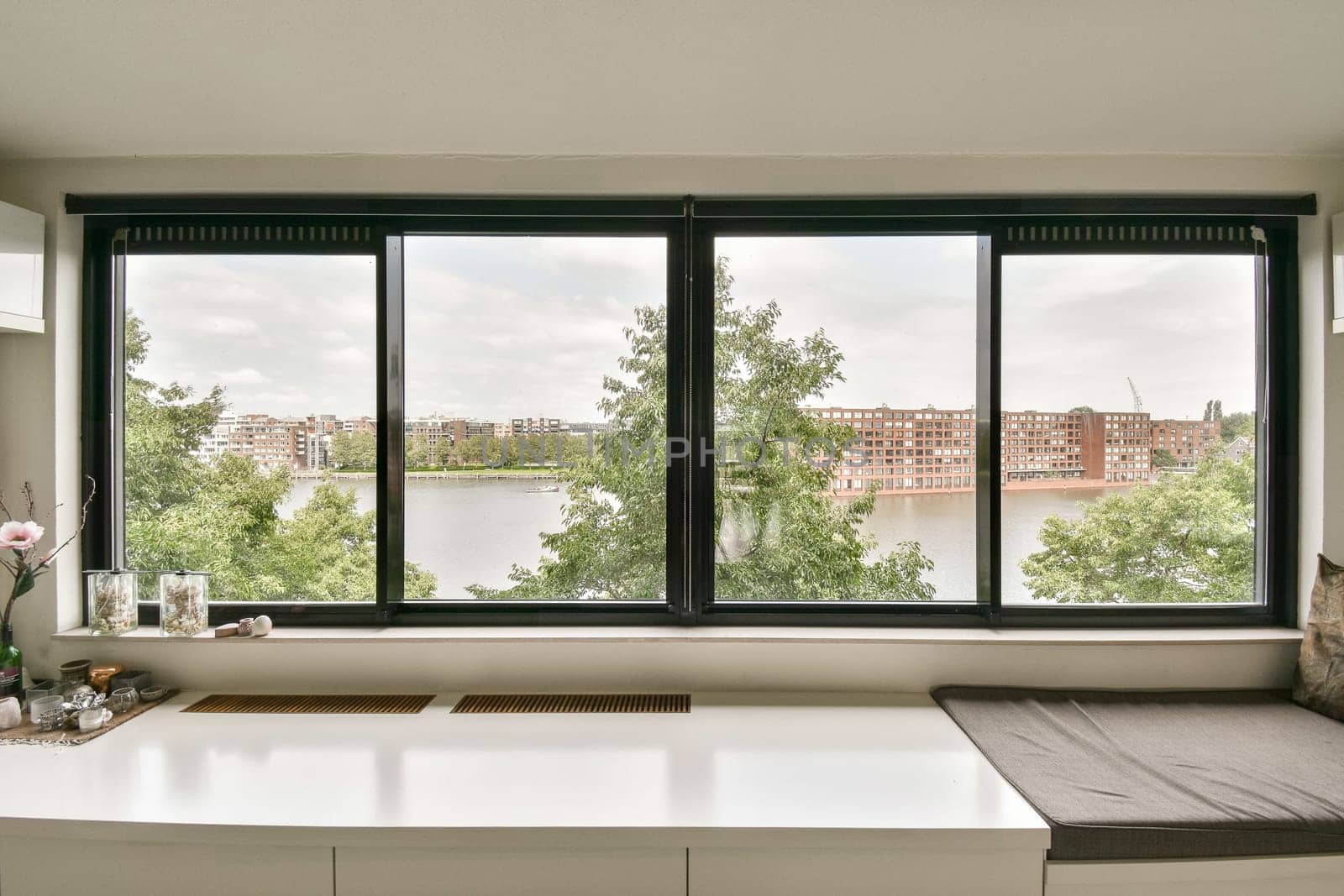 a window with a view of the water and buildings in the distance, as seen from an empty office space