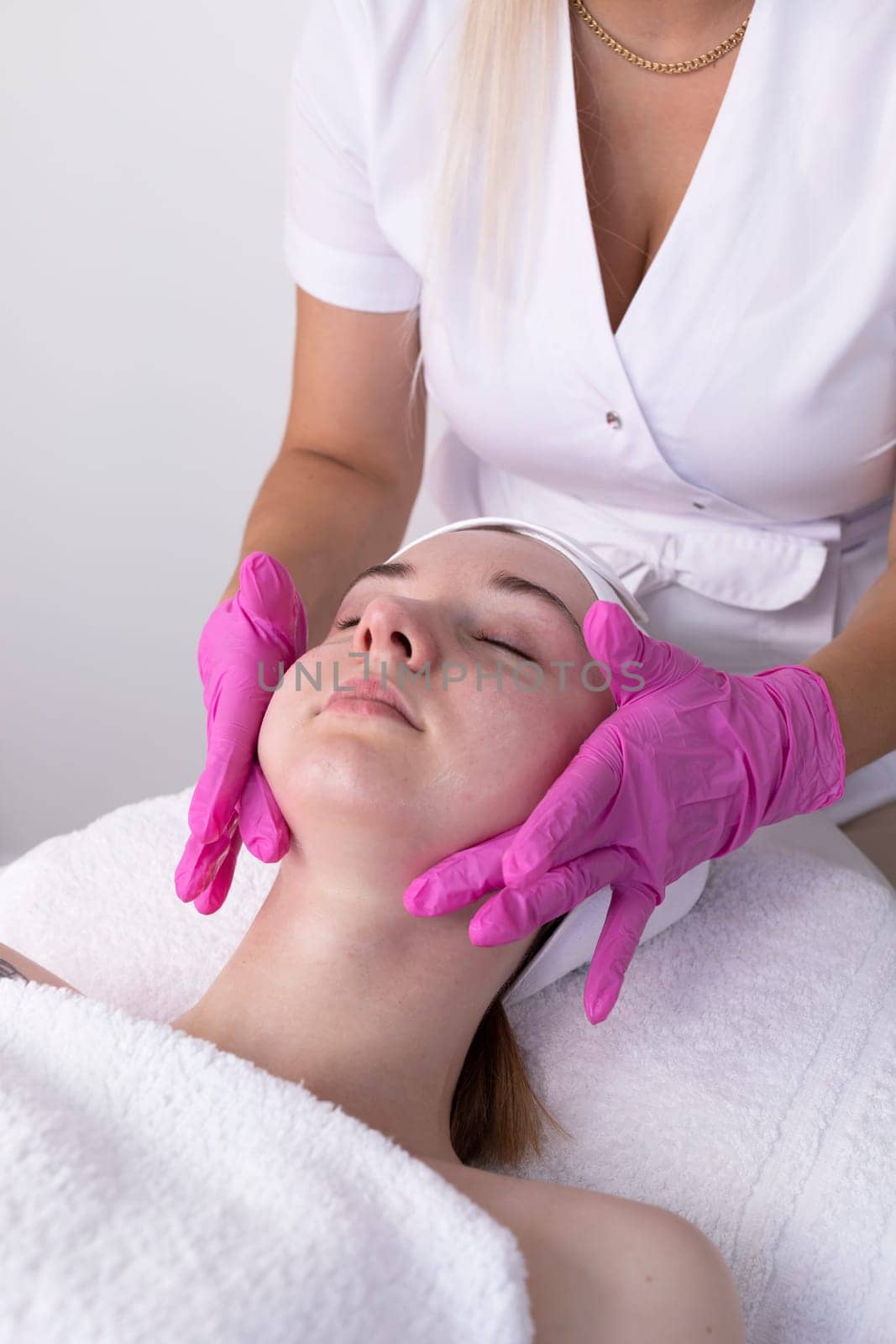Female Patient Receives Spa Facial Massage Treatment In Spa Salon. Relax And Stress Relief. Professional Skin Care Therapist Takes Care Of Woman. Top View. Vertical Plane, by netatsi