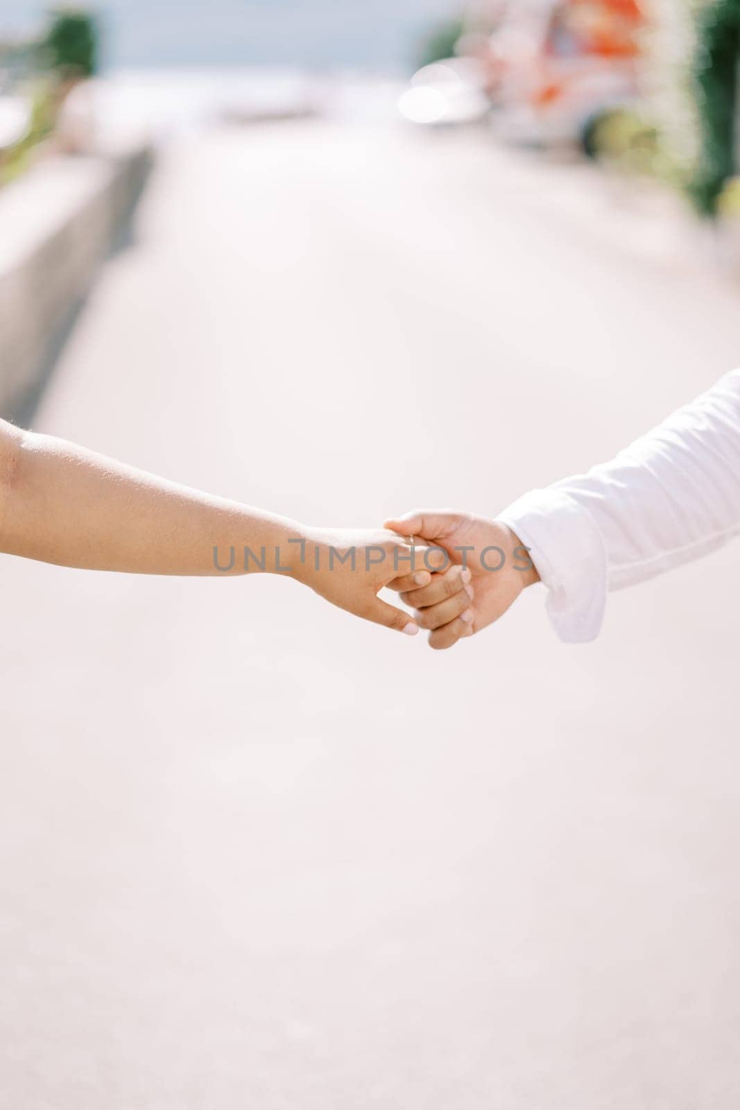 Man holds woman hand while standing on the road. Cropped. Faceless. High quality photo