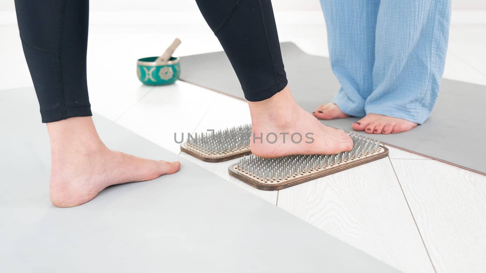 Caucasian woman stands on sadhu boards with therapist support