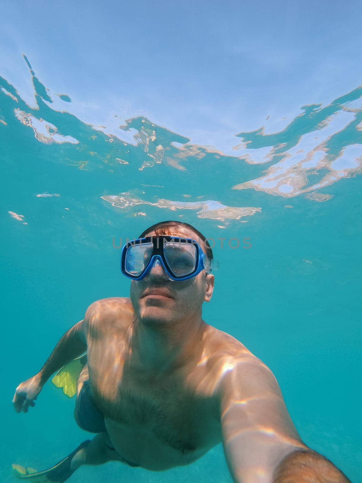 Young man in a swimming mask and fins swims underwater. High quality photo