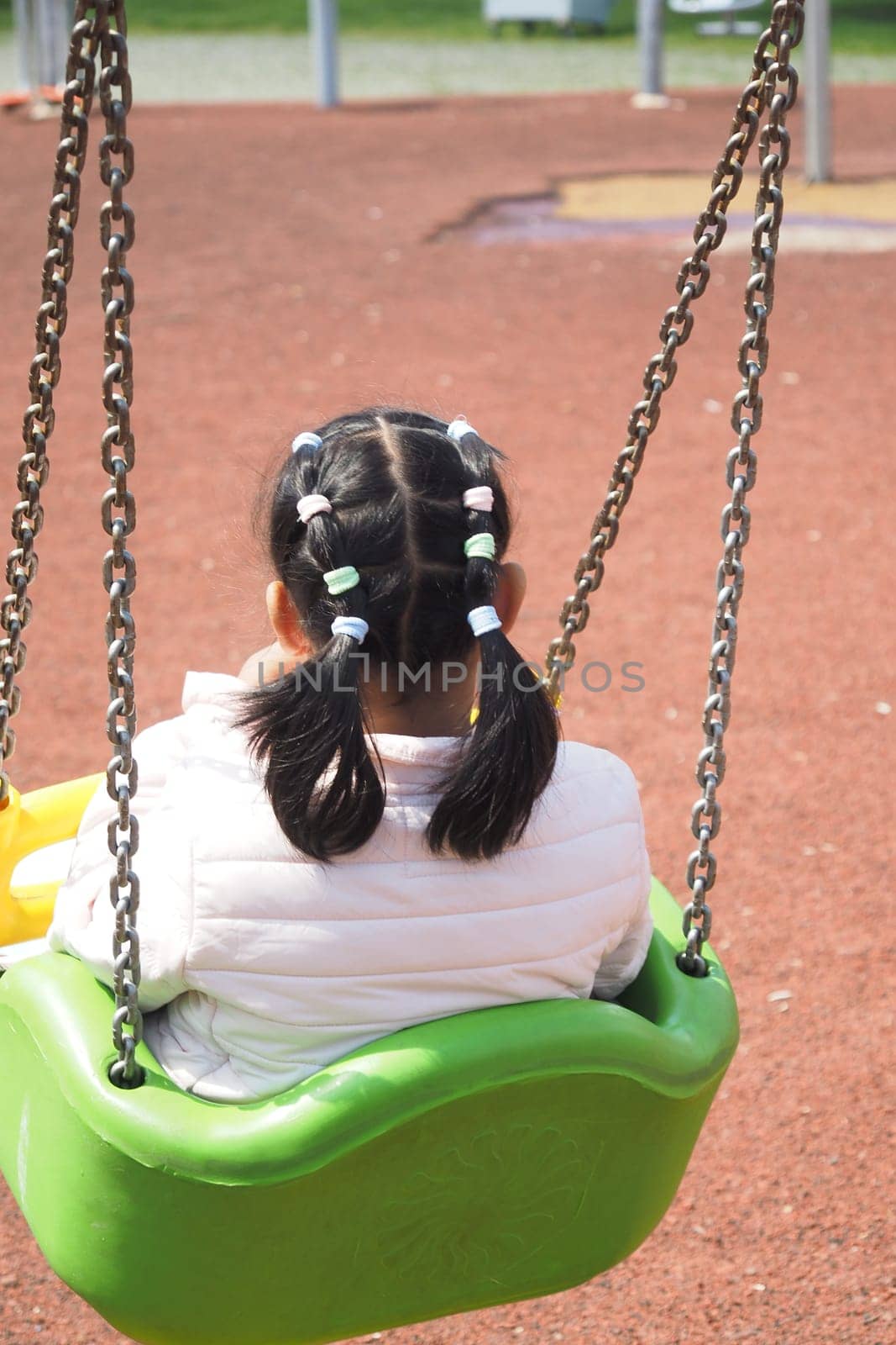 child having fun on a swing on the playground in public park