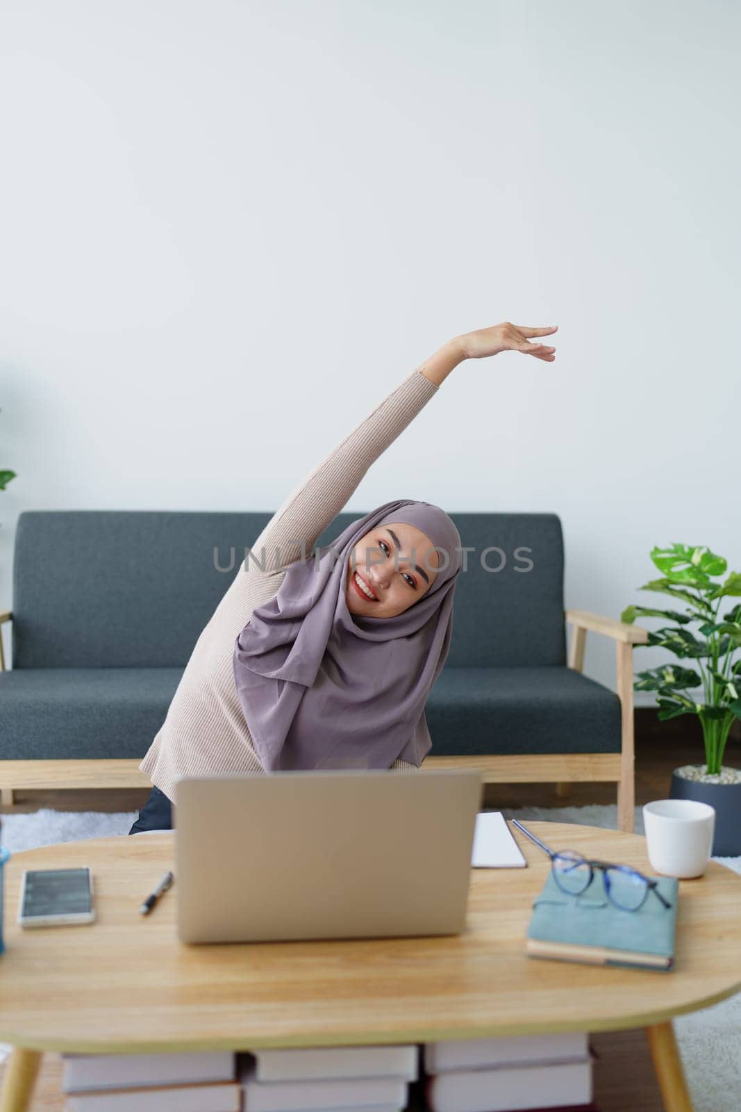 Muslim undergraduate students relax their muscles after taking online e-learning via computer system. by Manastrong