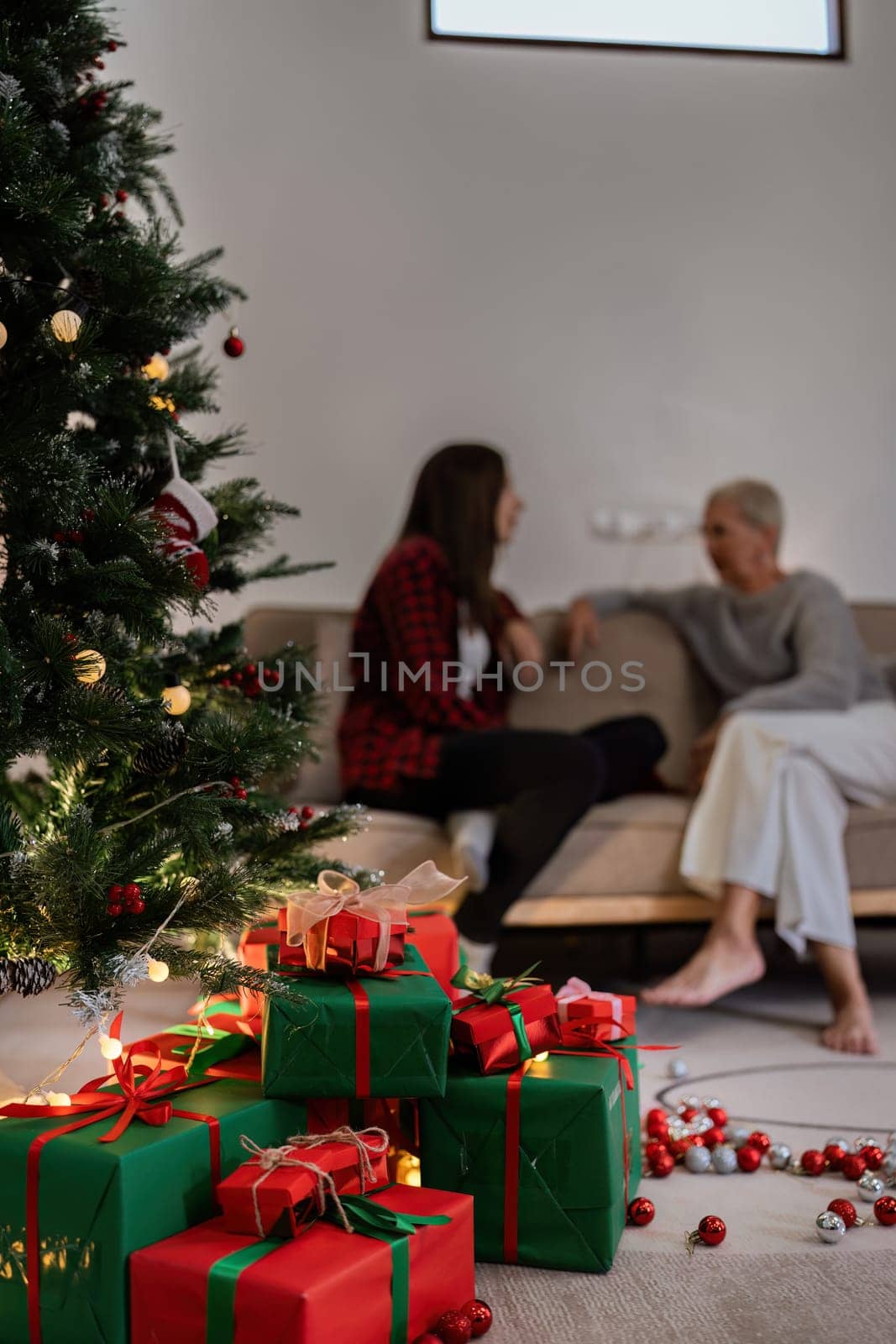 Beautiful Christmas gift boxes on floor near Christmas tree and have people background in room.