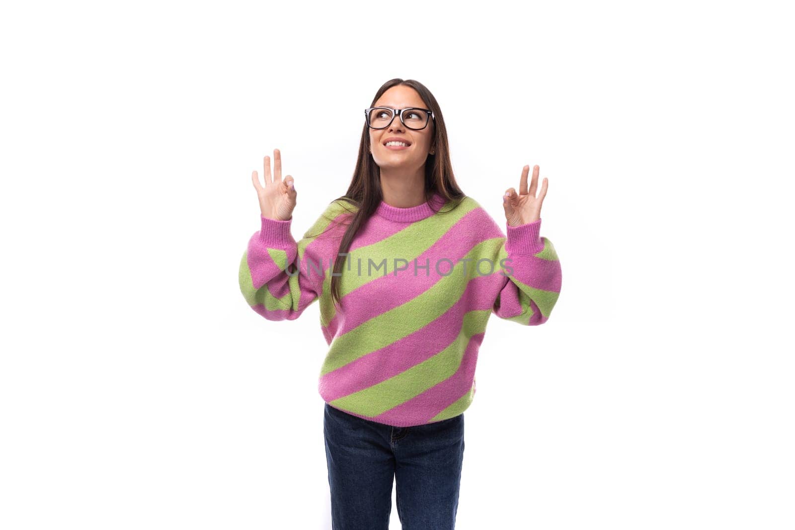 portrait of a young smart well-groomed caucasian woman with black hair in glasses dressed in a pink striped jacket pointing her hand to the idea.
