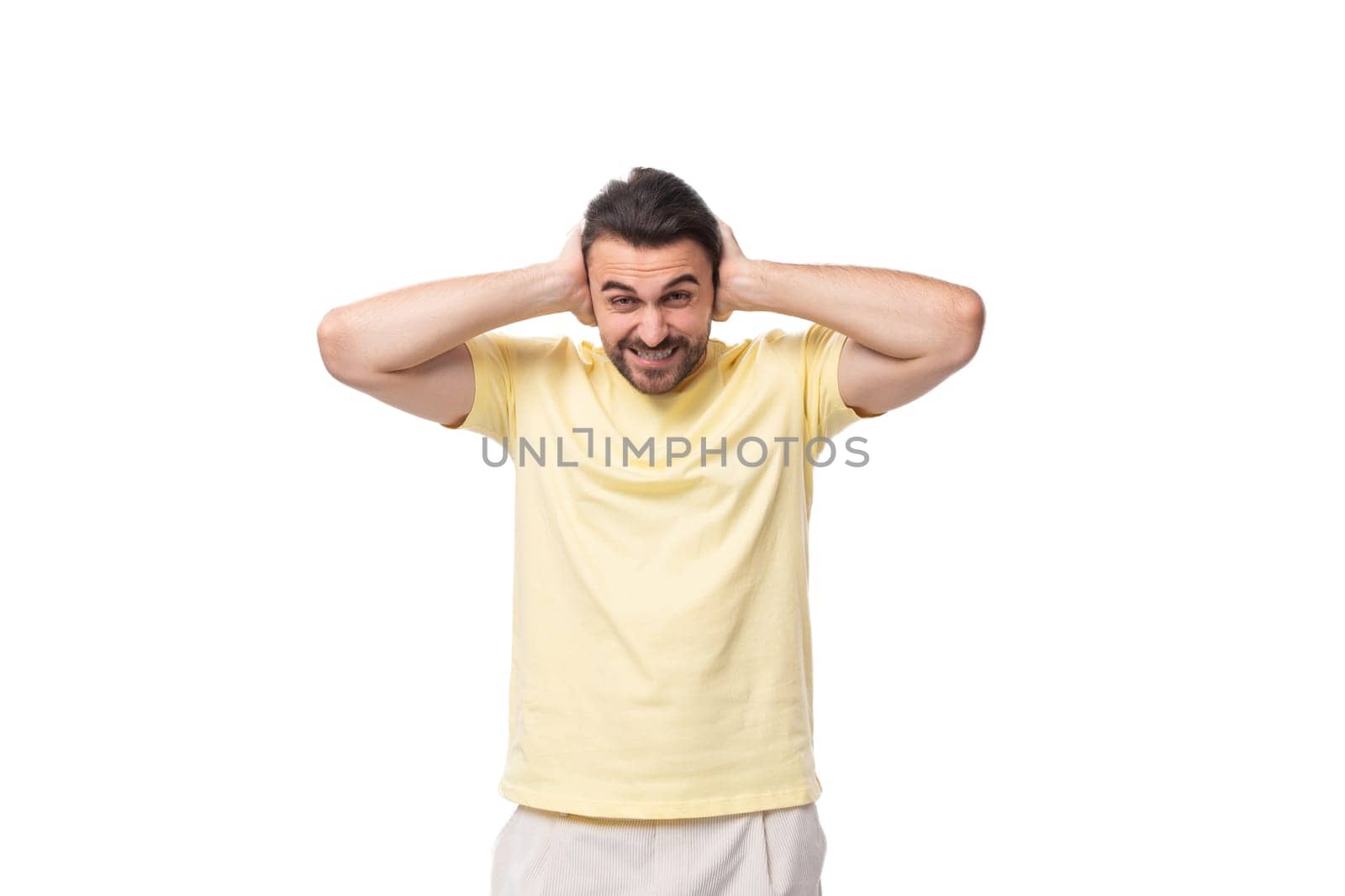 portrait of a fashionable young smart european guy with stubble and mustache dressed in a light yellow t-shirt on a white background.