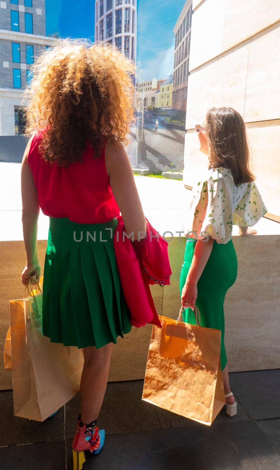 Two young beautiful girls walking the streets of the city with shopping bags by kajasja