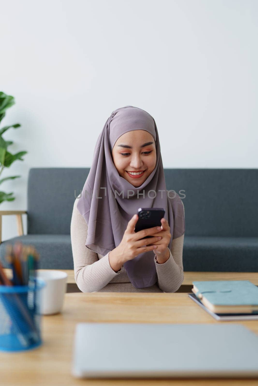 Muslim undergraduate student using mobile phone to contact friends