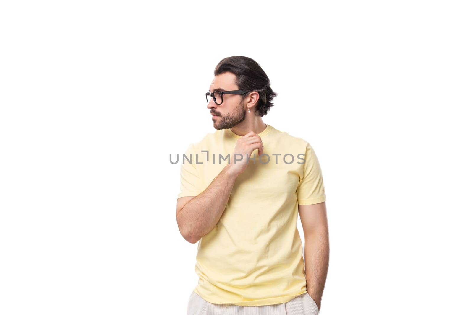 attractive young brunette man with a beard in a yellow t-shirt wears eyeglasses.