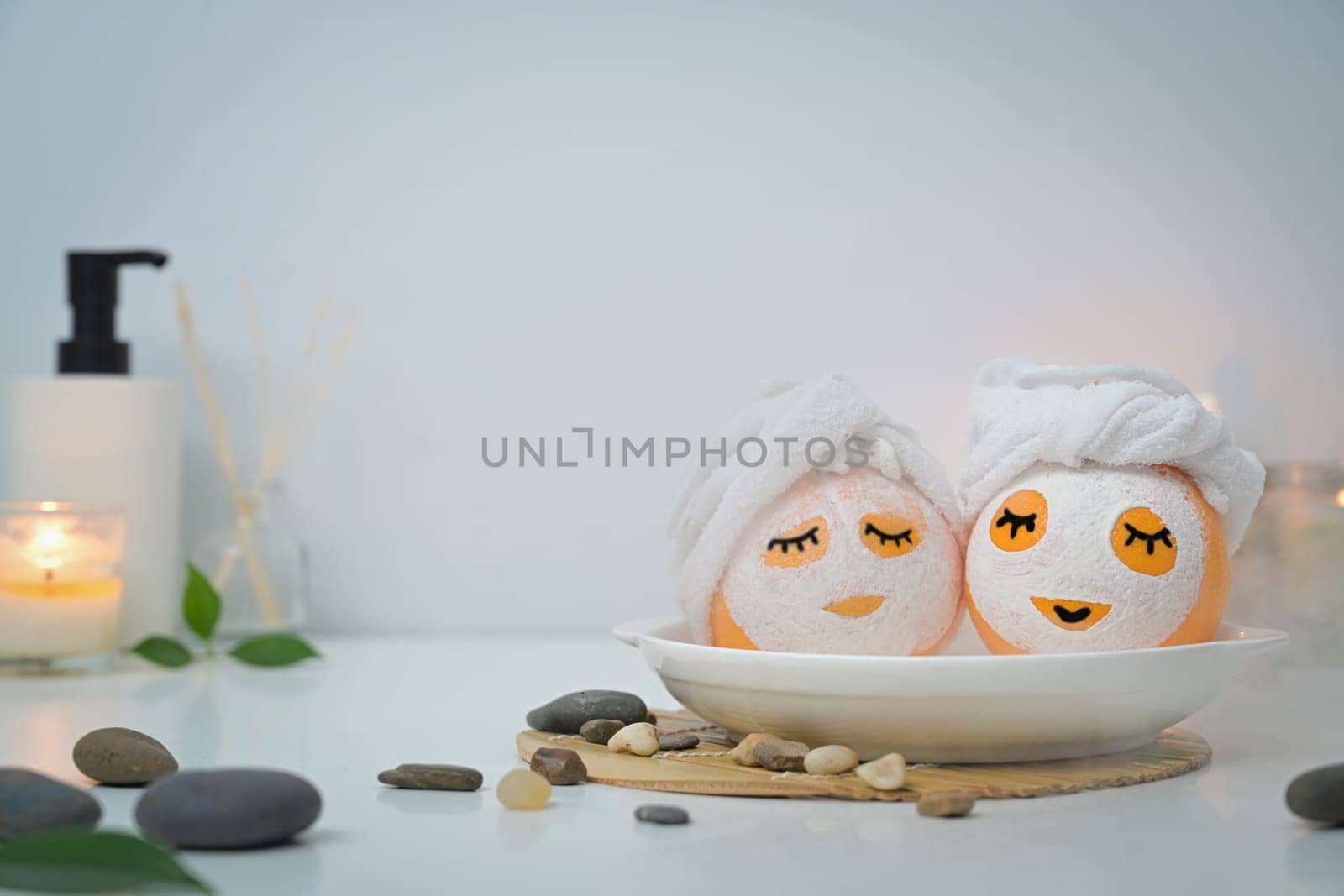 Two orange fruits in face mask looking like in bath or Onsen. Spa treatment and self care concept by prathanchorruangsak