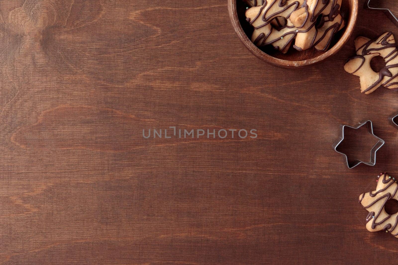 Freshly baked homemade star-shaped cookie with chocolate with cutters and wooden bowl on the wooden table with a copy space, horizontal banner