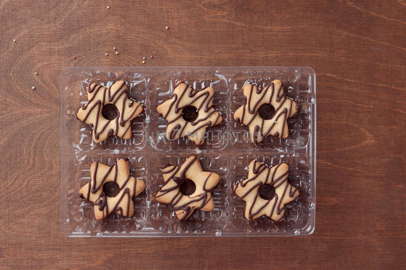 Star-shaped cookie with chocolate in the plastic box on the wooden table top view