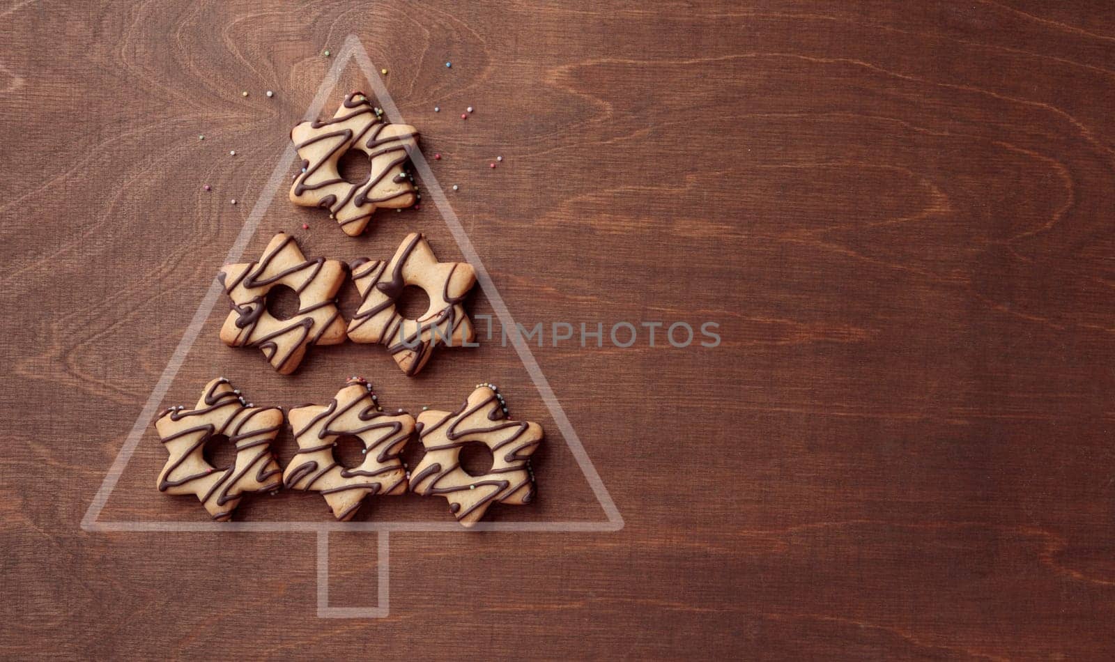 Christmas tree form made from star-shaped cookies with chocolate, banner on the brown wooden background with copy space