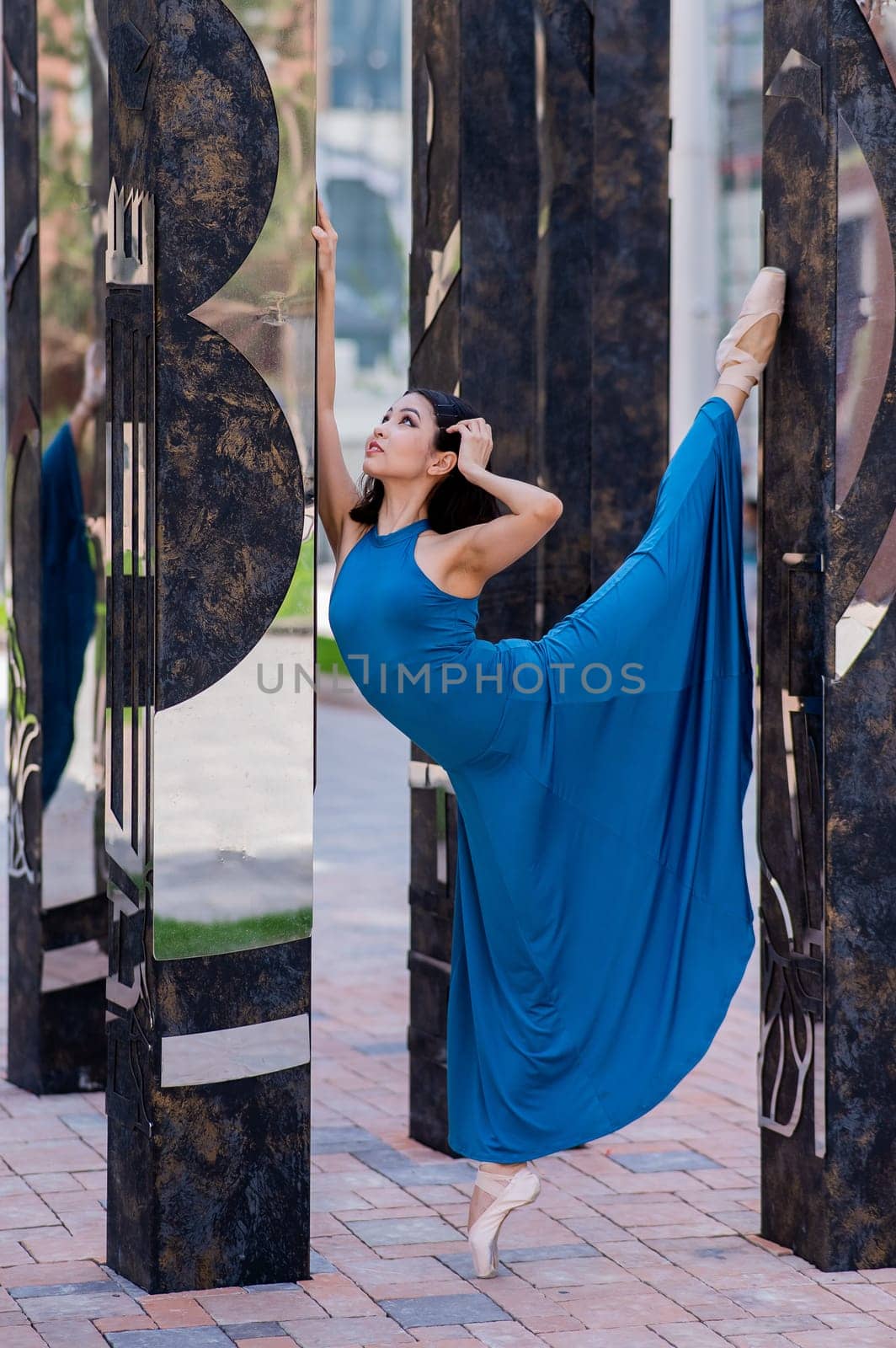 Beautiful asian ballerina in blue dress and pointe shoes posing outdoors. by mrwed54