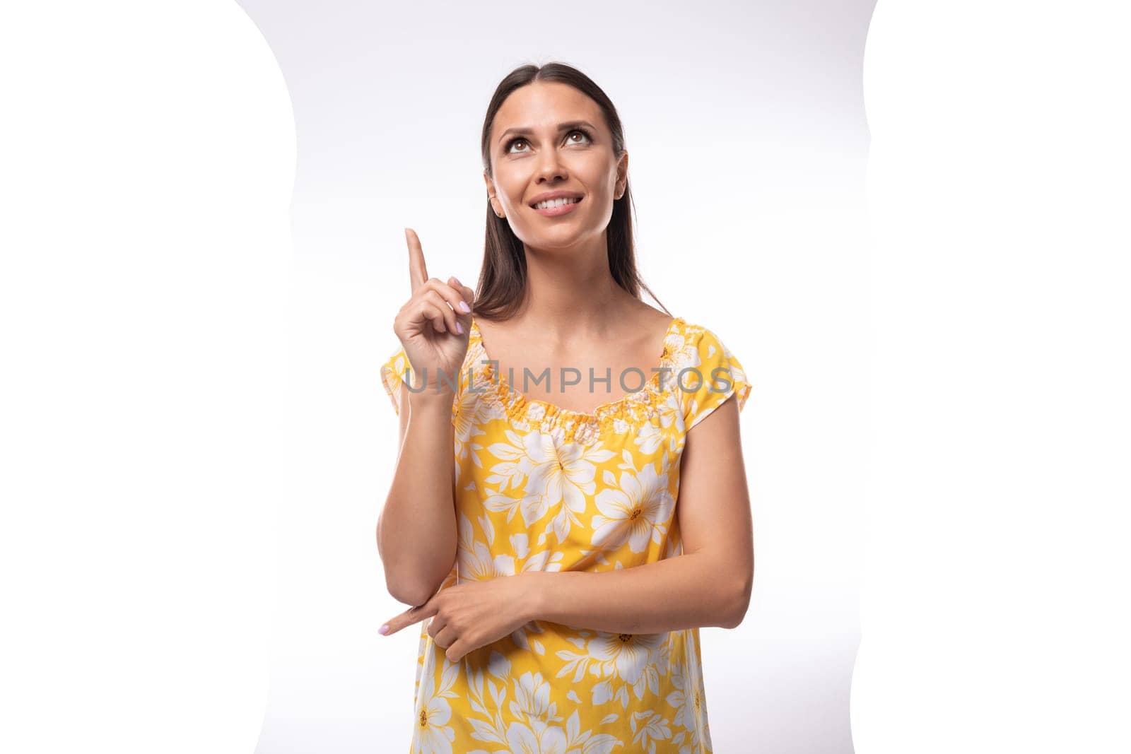 Caucasian young woman with straight black hair dressed in a yellow sundress gesturing with her fingers.