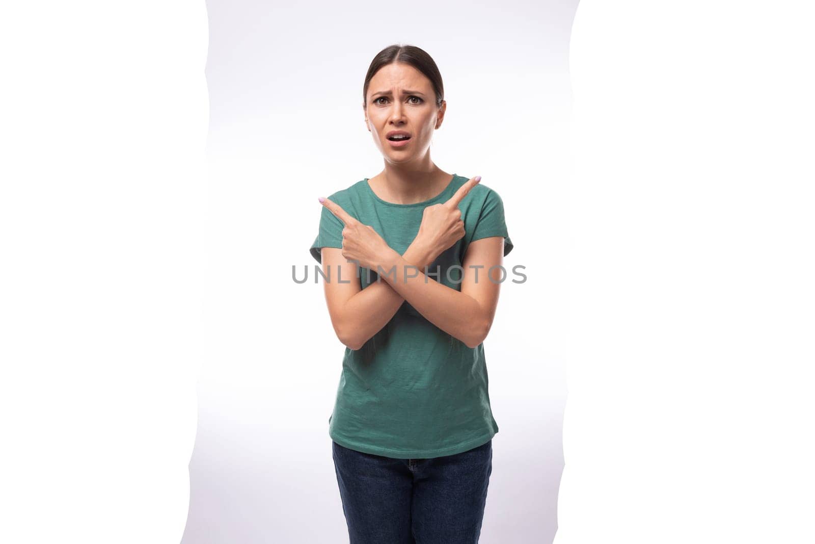 young beautiful brunette lady dressed in a green t-shirt and jeans crossed her arms in disagreement.