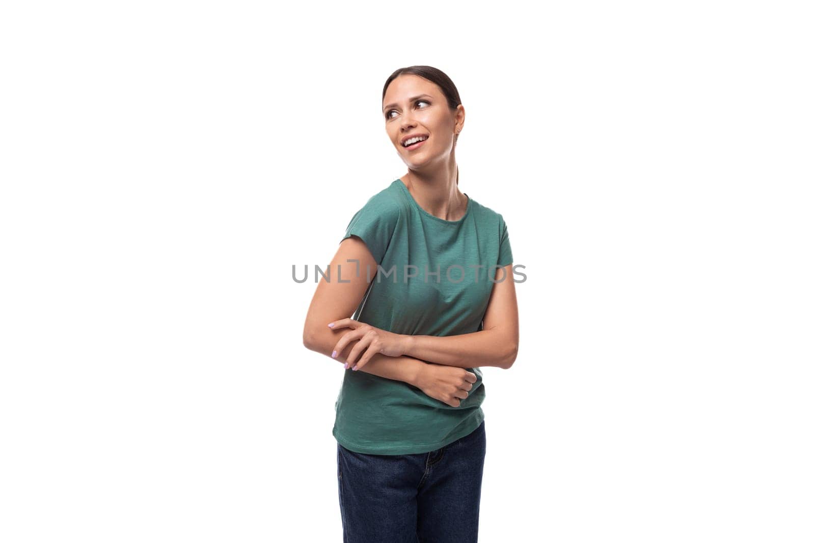 young woman in t-shirt and jeans looking away dreamily.