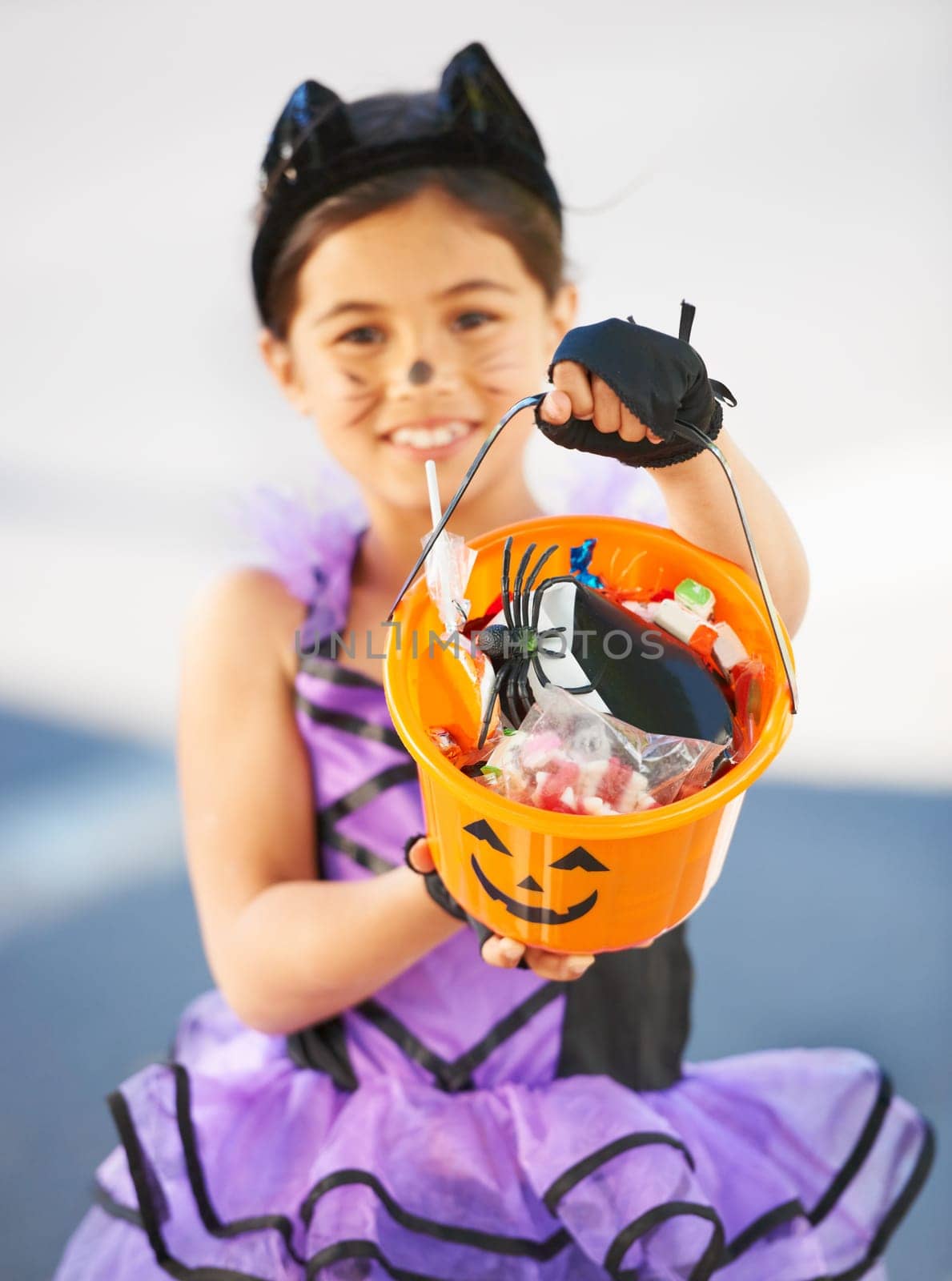 Want some Halloween candy. Little girl dressed in a Halloween costume holding a candy bucket