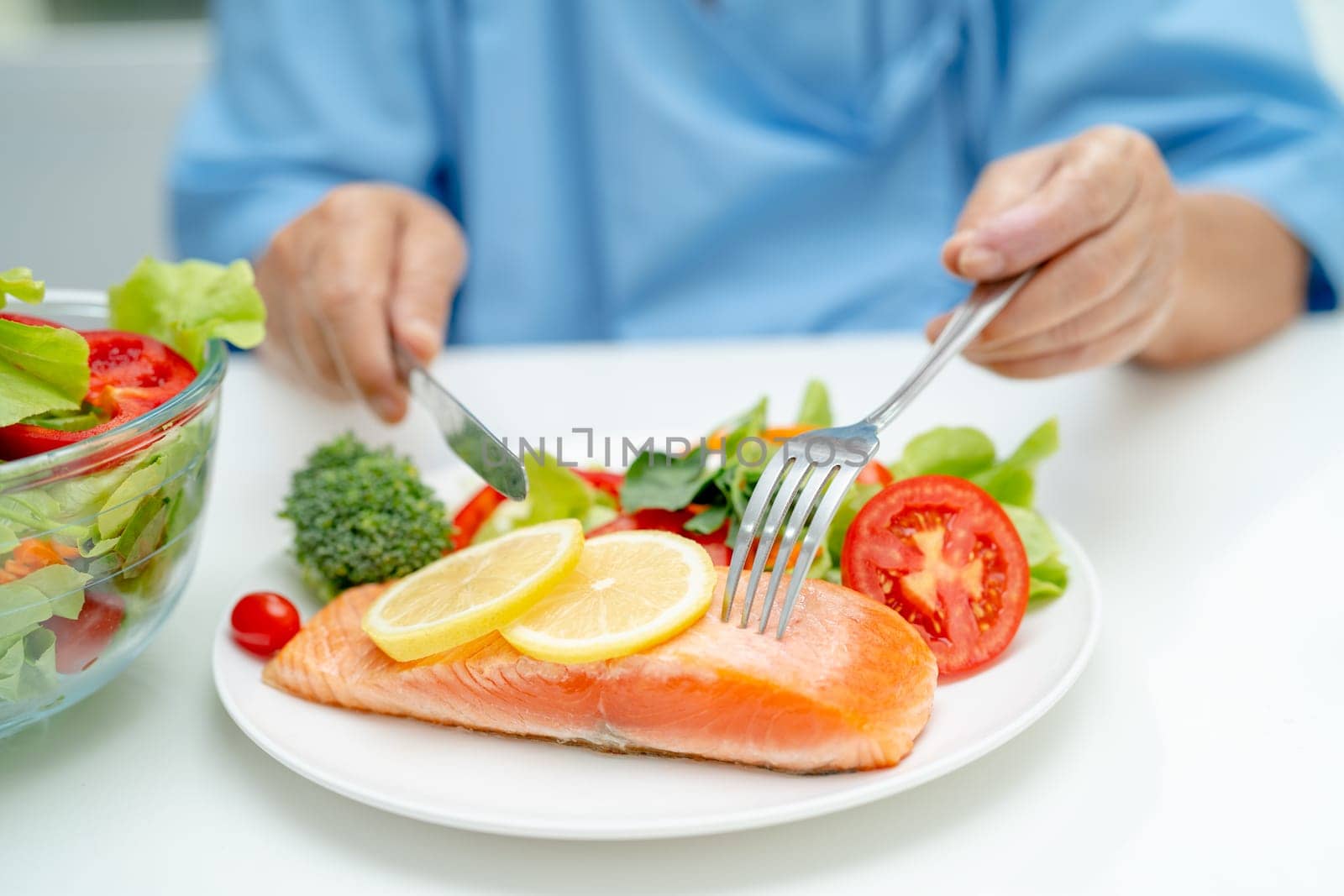 Asian elderly woman patient eating salmon steak breakfast with vegetable healthy food in hospital. by pamai