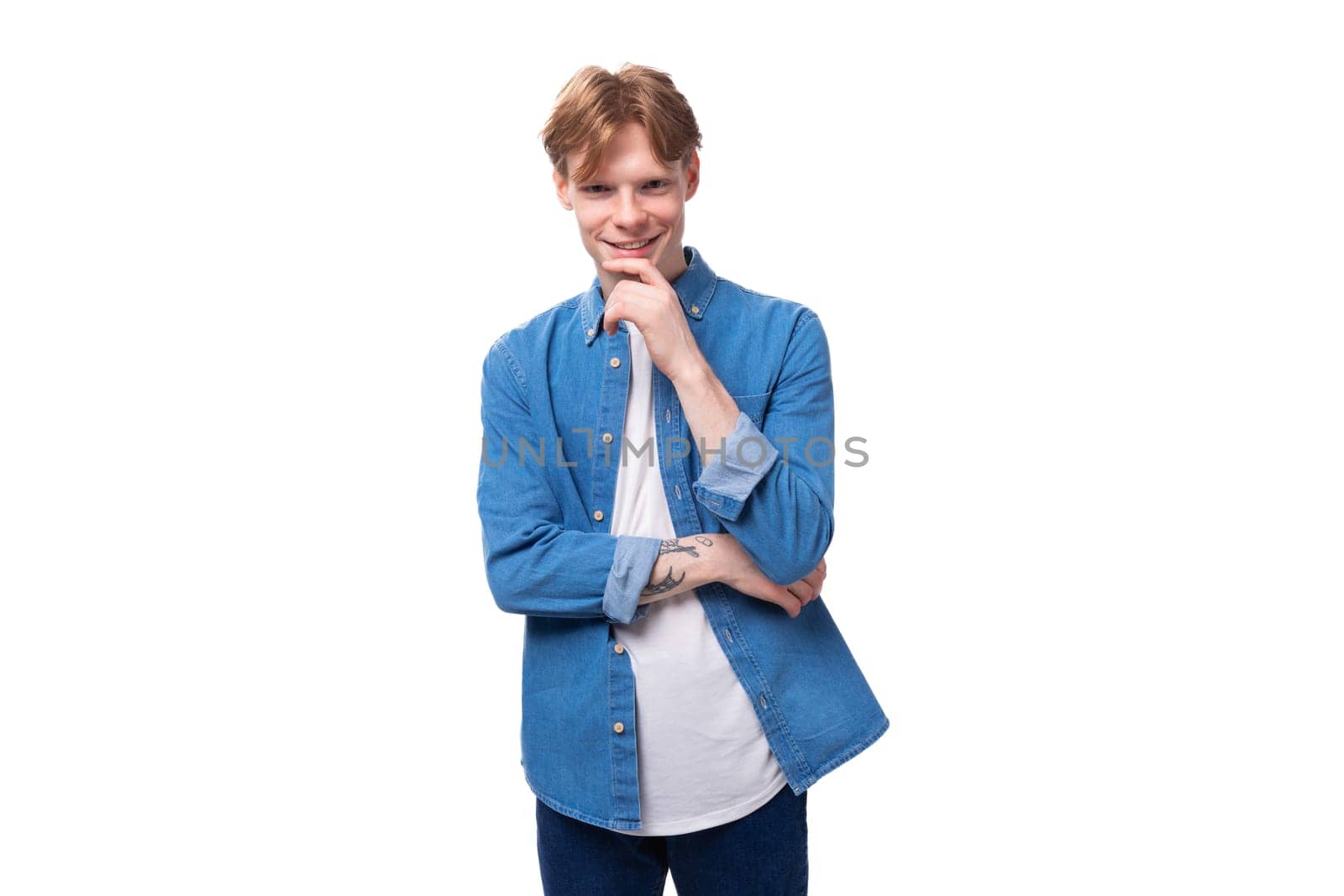 portrait of a smiling caucasian red-haired guy in a denim blue denim shirt on a studio background.