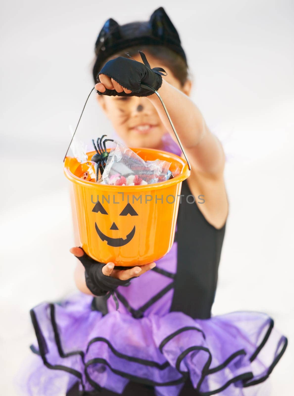 Look at all Ive got. Little girl dressed in a Halloween costume holding a candy bucket