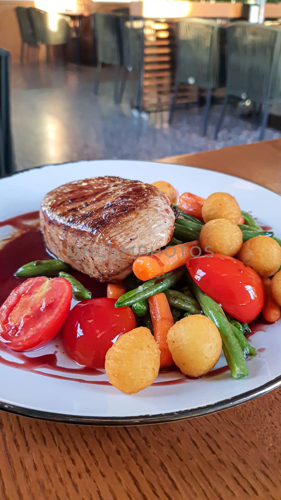 Beef steak with salad. Potato balls and various vegetables on a colored plate. Meat restaurant