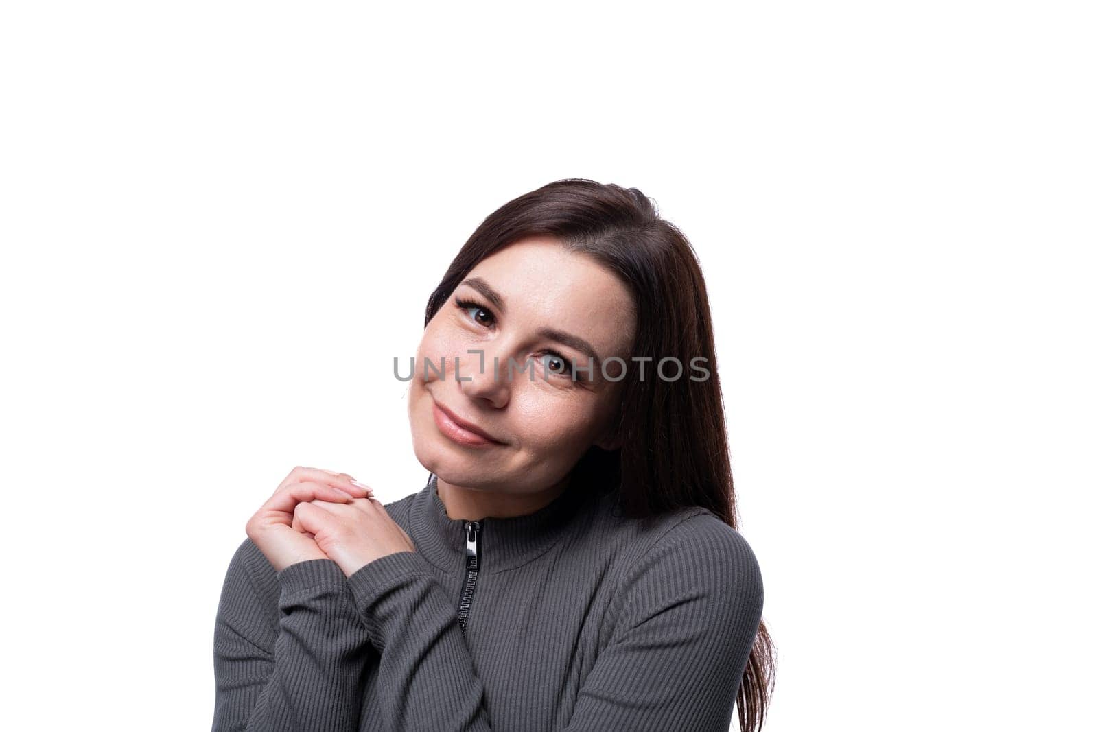 Young brunette woman smiling sweetly against a studio background with copy space by TRMK